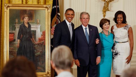 Former President George W. Bush stands next to then-President Barack Obama while former first lady Laura Bush stands next to then-first lady Michelle Obama during the unveiling of their official White House portraits in the East Room of the White House in May 2012.   