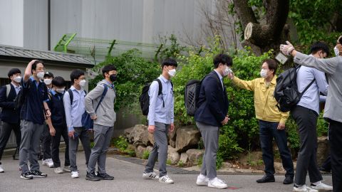 Students wearing face masks undergo a temperature check as they arrive at Keongbok High School in Seoul on May 20, 2020.