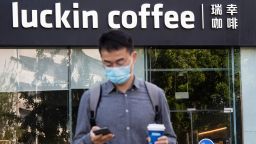 BEIJING, CHINA - MAY 20: A man wearing a face mask looks at his smartphone in front of a Luckin Coffee store on May 20, 2020 in Beijing, China. (Photo by Hou Yu/China News Service via Getty Images)