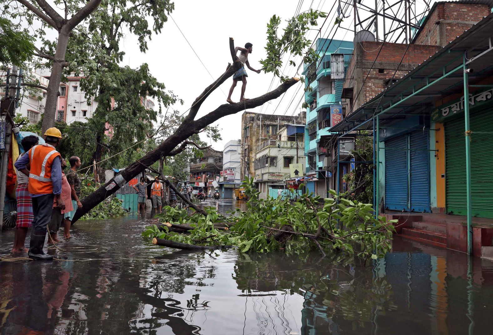 A man cuts branches from an uprooted tree in Kolkata on May 21.