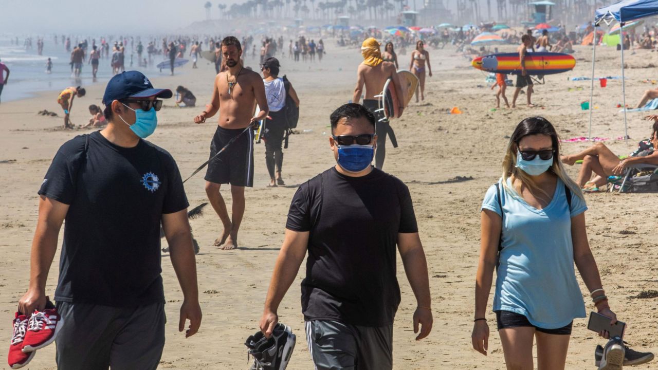 People on the beach, some wearing masks, amid the pandemic in Huntington Beach, California.