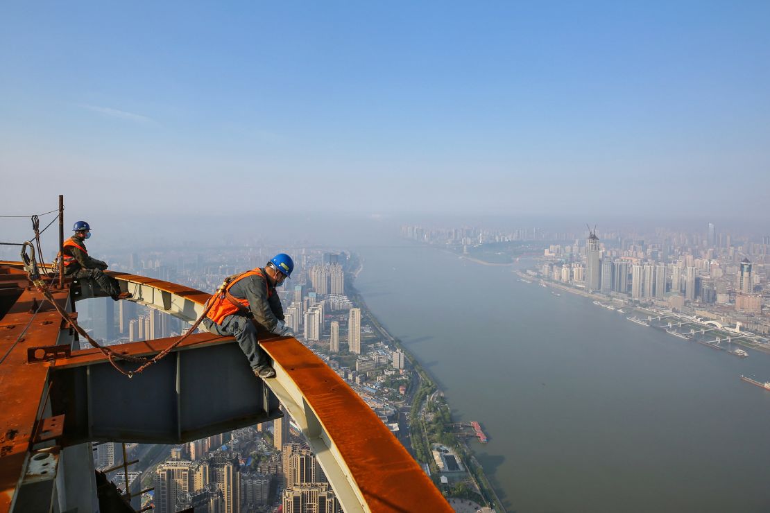Workers atop the Wuhan Greenland Center, which remains unfinished eight years after construction commenced.  