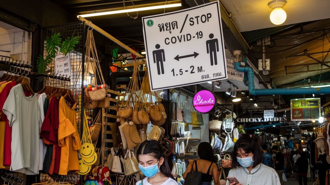 <strong>Chatuchak Weekend Market: </strong>Shoppers wearing face masks walk past a sign reminding visitors to observe social distancing at Bangkok's Chatuchak Weekend Market on May 17.