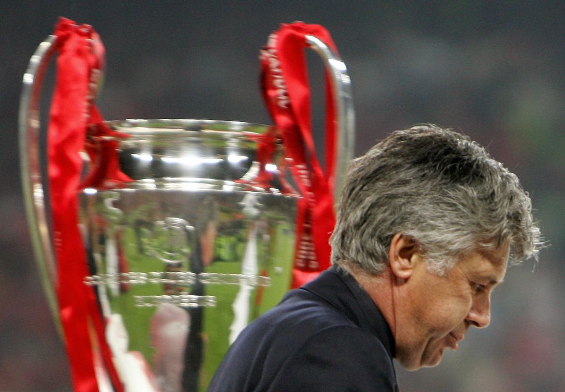 AC Milan coach Carlo Ancelotti walks past the Champions League trophy.