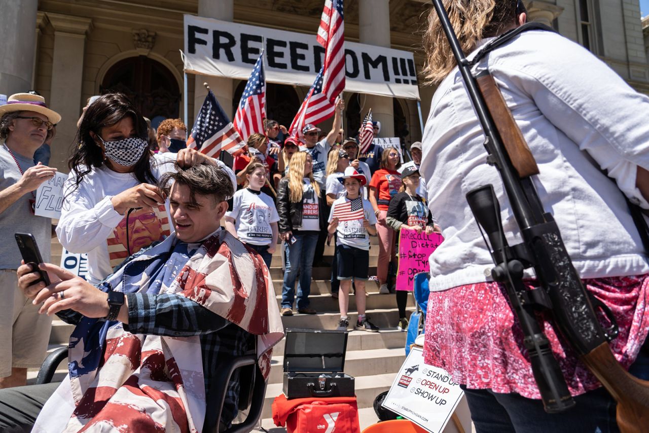 Jeff Sizemore has his hair cut on the front steps of the Michigan State Capitol during a protest in Lansing on Wednesday, May 20. Some people were armed during the protest, which opposed the state's stay-at-home order.
