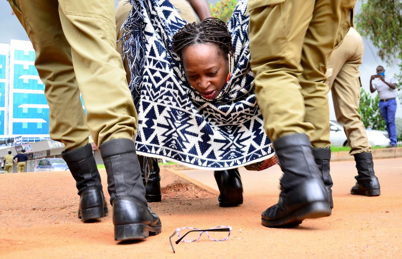 Stella Nyanzi looks at her glasses as police officers detain her during an anti-government protest in Kampala, Uganda, on Monday, May 18.