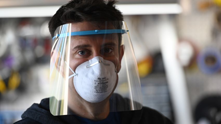 Jeremy Reitman poses wearing one of the medical quality personal protective equipment (PPE) face shields for doctors and nurses that he is making in his garage on 3D printers in Calabasas, California, March 30, 2020. - From amateur seamstresses and sewing clubs to Hollywood costume-makers, a patchwork army of volunteers across the United States is churning out gowns and masks for emergency workers battling coronavirus. Reitman asked friends for donations to buy many more printers, filament printing material, clear PVC plastic sheets and elastic bands to manufacture the face shields needed by hospitals in Los Angeles and across the country. He plans to donate all printers and materials to schools when the crisis is over. (Photo by Robyn Beck / AFP) (Photo by ROBYN BECK/AFP via Getty Images)