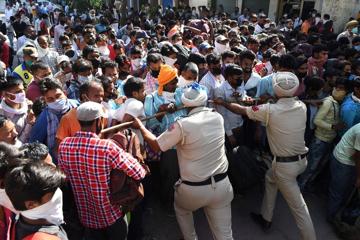 Police officers push back stranded migrant workers who were gathering for a medical screening before boarding a train in Amritsar, India, on Wednesday, May 20.