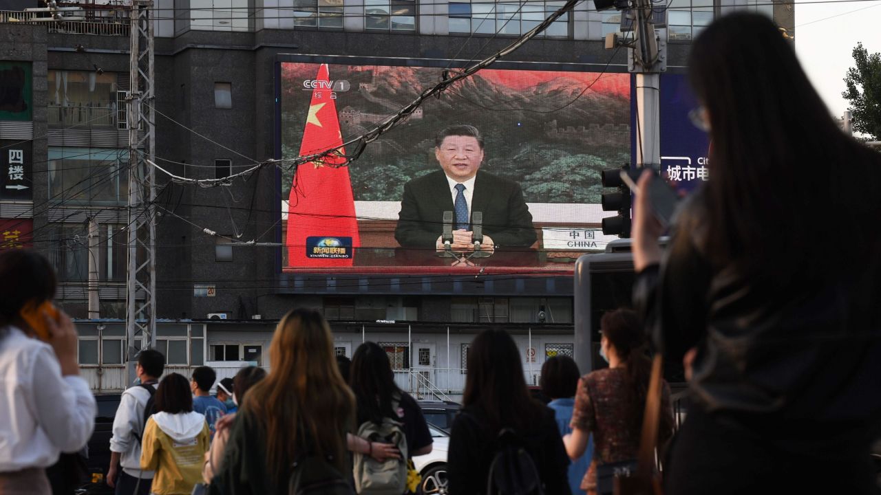 A news program shows Chinese President Xi Jinping speaking via video link to the World Health Assembly, on a giant screen beside a street in Beijing on May 18, 2020.  