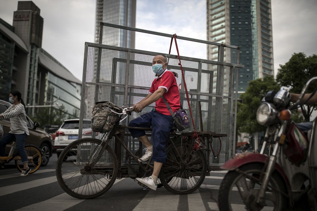 A man wearing a face mask ride tricycles to transport iron nets in Wuhan on May 11.