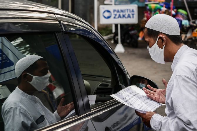 An officer wearing a protective mask gathers Zakat al-Fitr, or charity, during the holy month of Ramadan with a drive-through system as preventive measures against the spread of the coronavirus at Nurul Hidayah Mosque in Jakarta, Indonesia on May 21. 