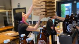 An employee at Zeeks Pizza prepares for the lunch take-out and delivery rush at the restaurant's Capitol Hill location on April 9, 2020, in Seattle, Washington. A temporary loosening of Washington's alcohol laws have allowed for restaurants such as Zeeks to deliver draft beer in 64-ounce glass growlers. Photo courtesy: Zeeks Pizza