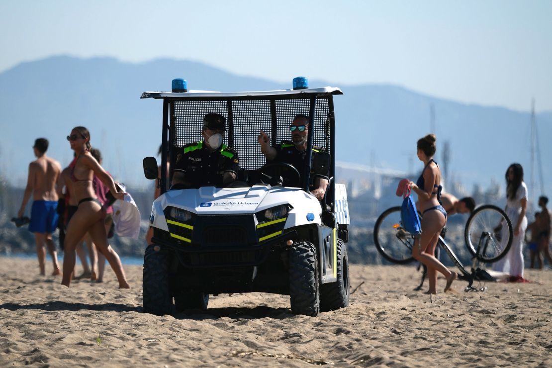 Spanish policemen ask people that were sunbathing to leave the Barceloneta beach in Barcelona on May 20, 2020 during the hours allowed by the government to exercise.