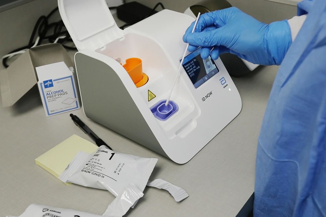 A lab technician dips a sample into the Abbott Laboratories ID Now testing machine at the Detroit Health Center.