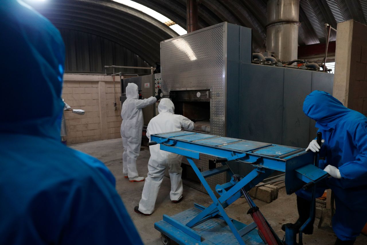 Workers wear protective gear as they start a cremation oven in Ecatepec, Mexico.