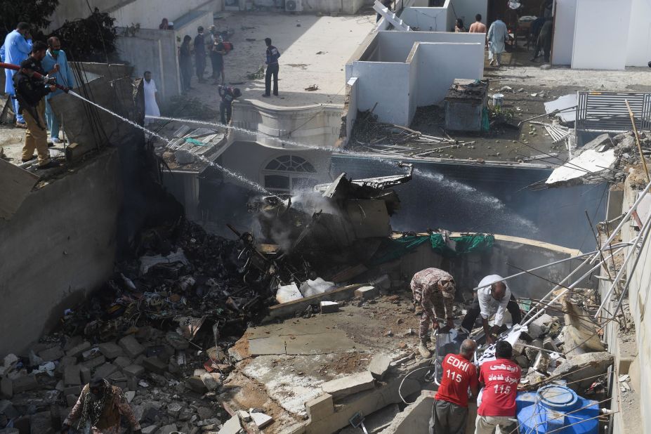 Crews spray water on the smoldering wreckage of the plane.