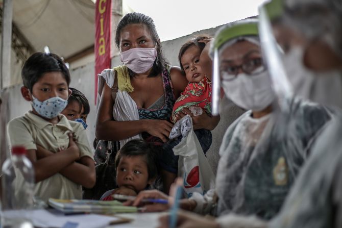 An indigenous woman holds her children while waiting on testing in Manaus on May 21.