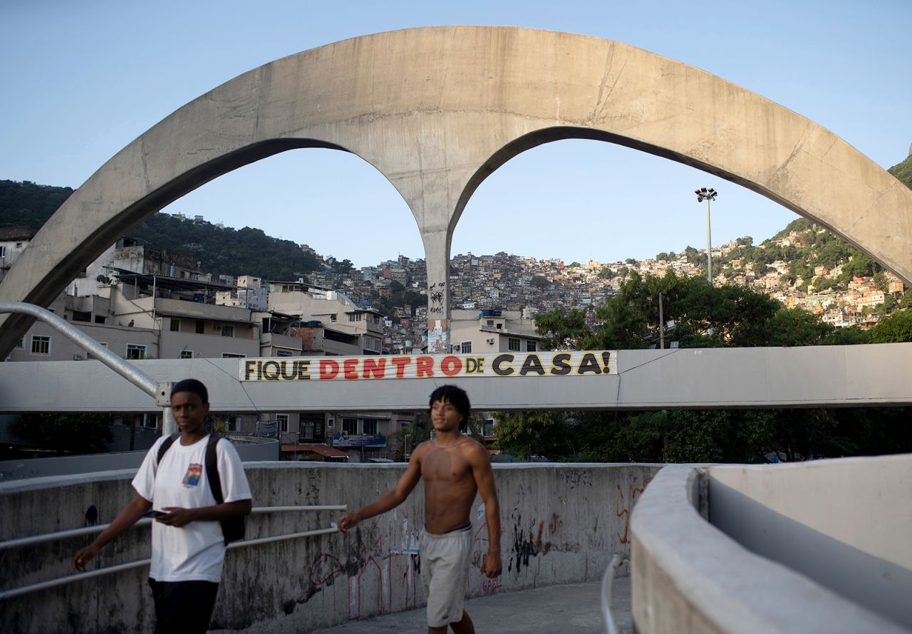 Men in Rio walk past a banner on April 6 that reads "stay at home" in Portuguese.