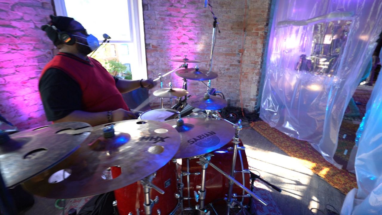 "Biscuit" Bynum, drummer for The Band with No Name, plays behind a wall of plastic sheets.