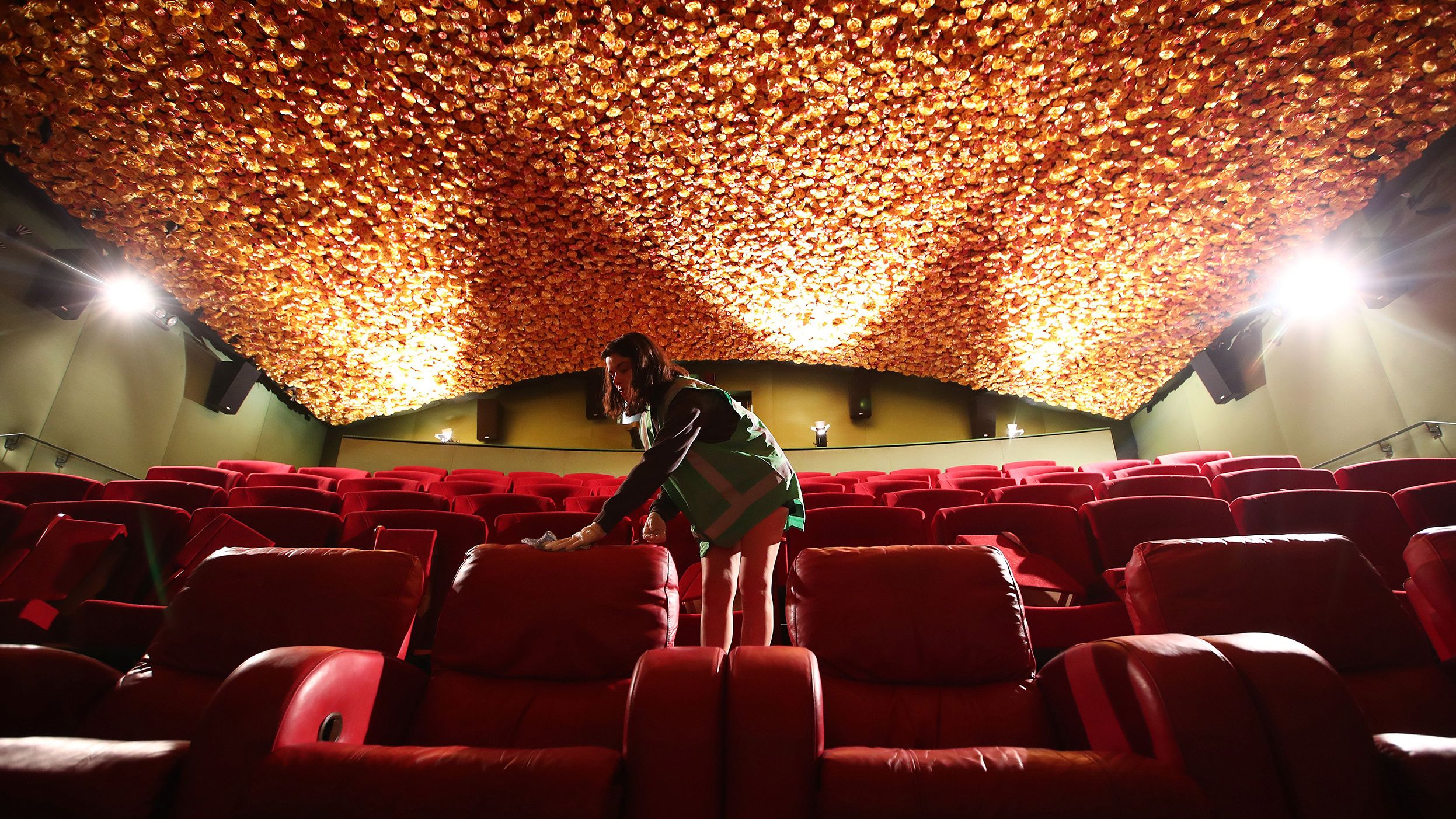 Jasmine Donaldson cleans a movie theater in Auckland, New Zealand, on May 22. Matakana Cinemas reopened May 28 with a reduced capacity to allow for social distancing between seats and in the foyer.