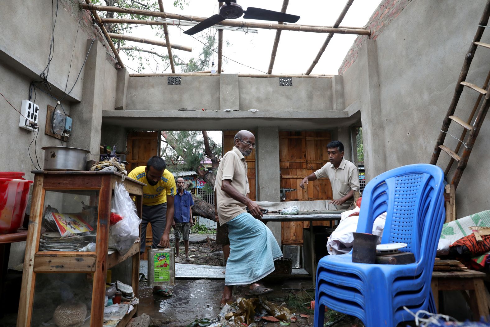 Men salvage items from a damaged shop in West Bengal on Thursday, May 21.