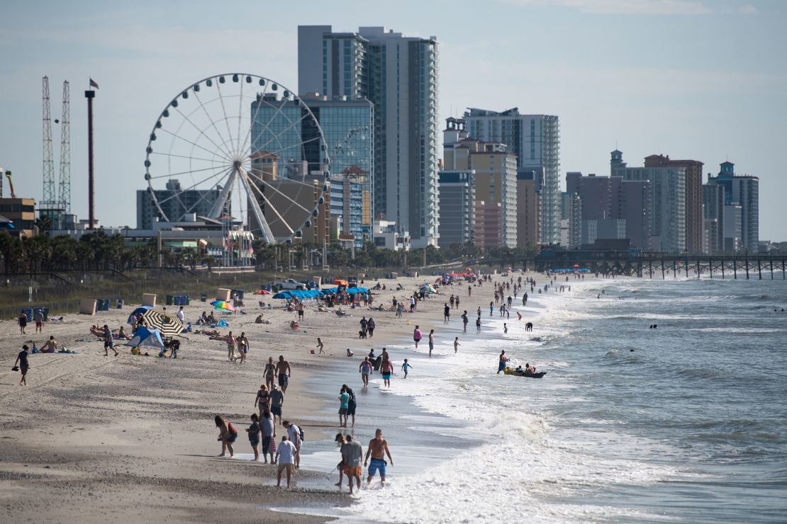 People walk and gather  along the beach on Saturday morning in Myrtle Beach, South Carolina.