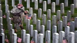 ARLINGTON, VA - MAY 21: A member of the military places a flag near a headstone at Arlington National Cemetery in advance for Memorial Day on Thursday May 21, 2020 in Arlington, VA. (Photo by Matt McClain/The Washington Post via Getty Images)