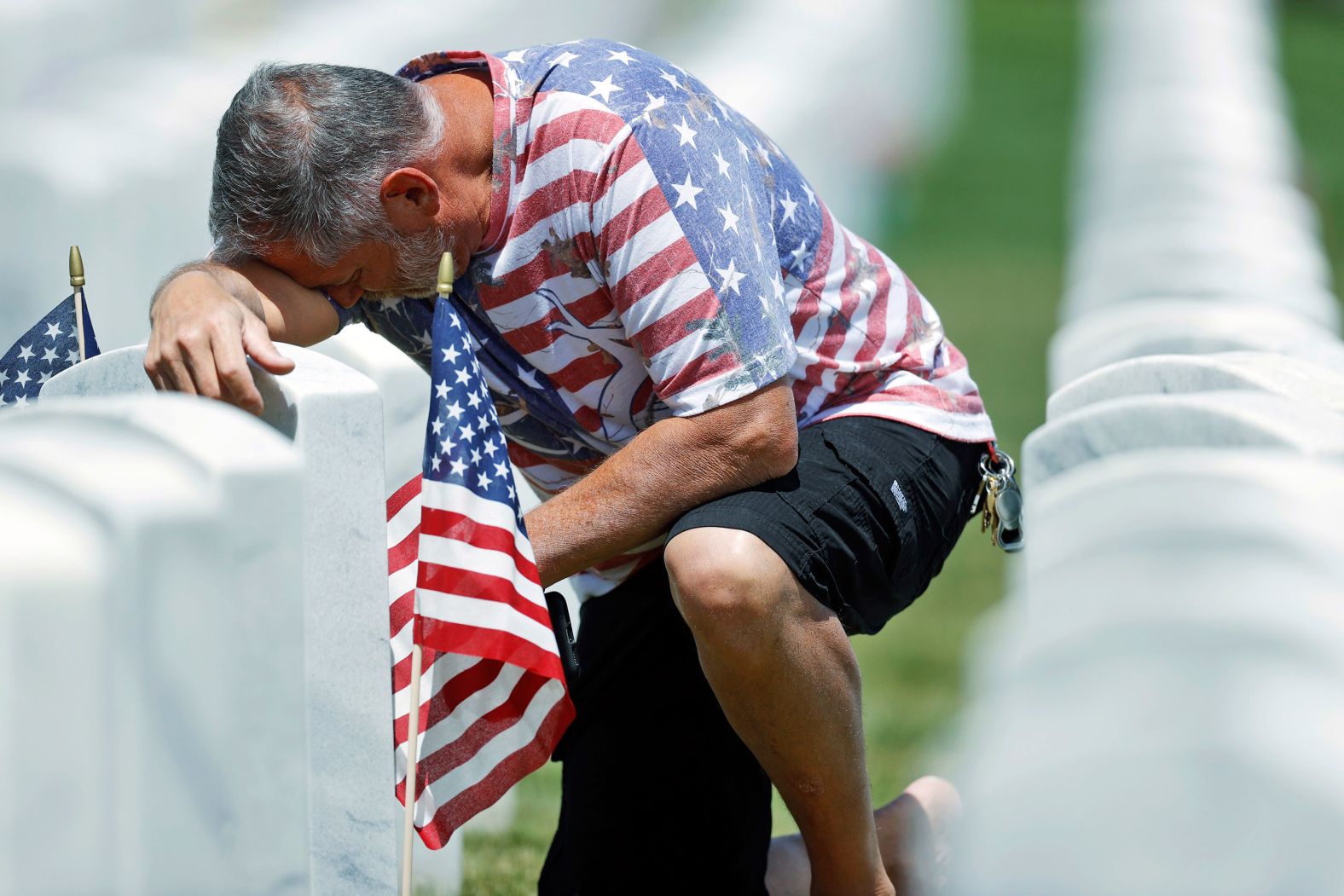 J.D. Madrid pauses for a moment at the grave of his father-in-law, Michael McBrien, in Fort Logan National Cemetery, in Sheridan, Colorado, on Saturday.