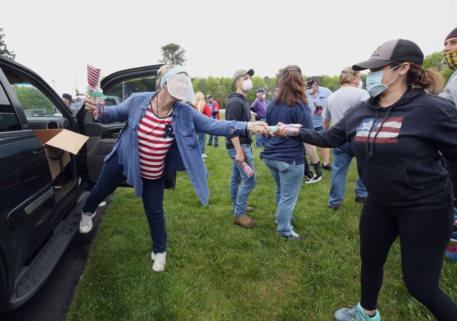 Holly Meyer hands out flags to volunteers to place at the Calverton National Cemetery in Wading River, New York, on Saturday. The US Department of Veterans Affairs suspended the practice amid concerns about the coronavirus pandemic leading volunteer groups to take action on Memorial Day weekend.