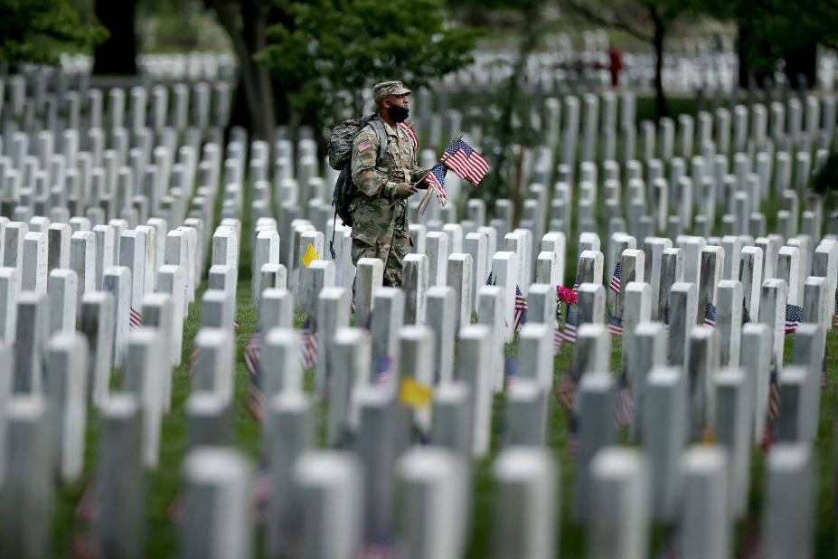 Soldiers from the 3rd Infantry Regiment, also called the "Old Guard," place US flags in front of every grave site ahead of Memorial Day weekend in Arlington National Cemetery on Thursday, May 21.