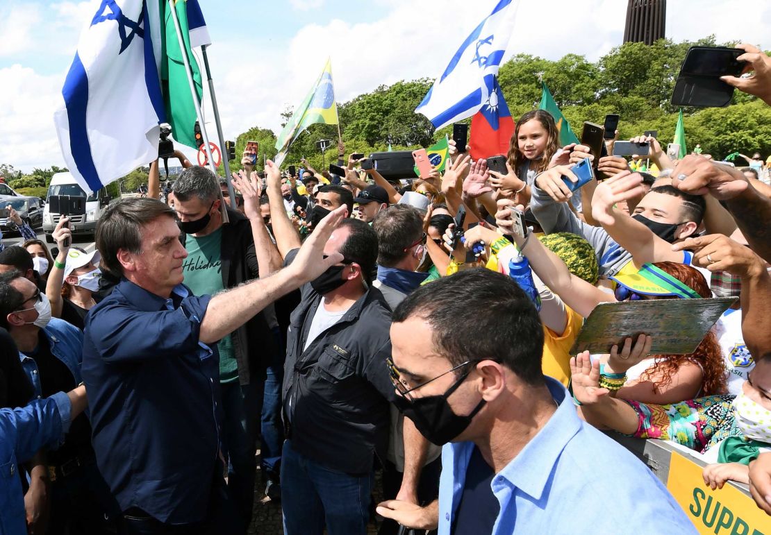 Brazil's President Jair Bolsonaro greets supporters upon arrival at Planalto Palace in Brasilia, on May 24.