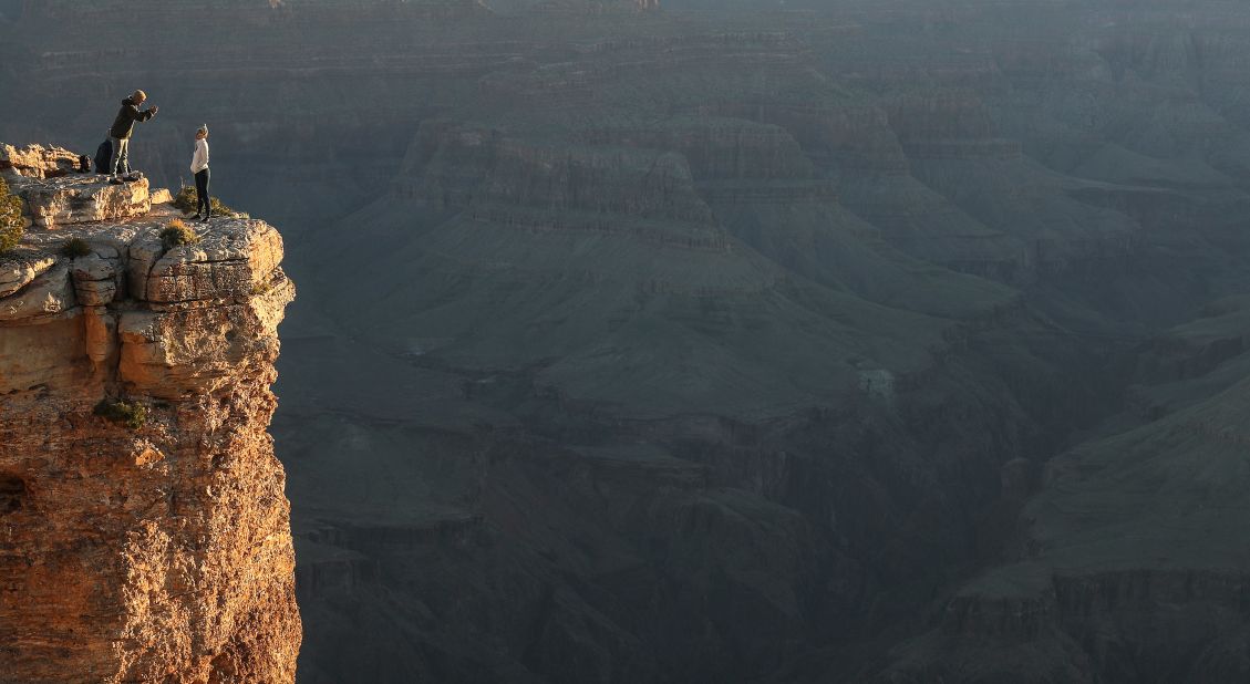 Visitors take photos from the South Rim of the Grand Canyon shortly after sunrise on May 25. Grand Canyon National Park had partially reopened for weekends.