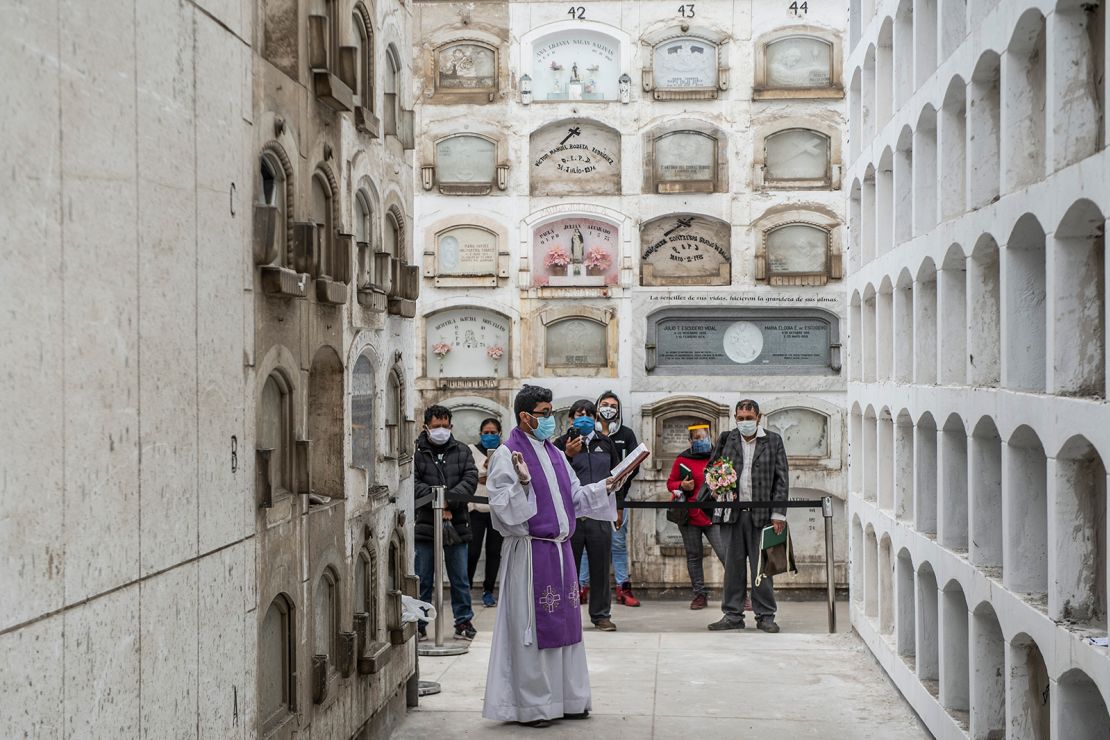 A priest conducts a ceremony after the funeral of Covid-19 victims at El Angel cemetery, in Lima on May 21.