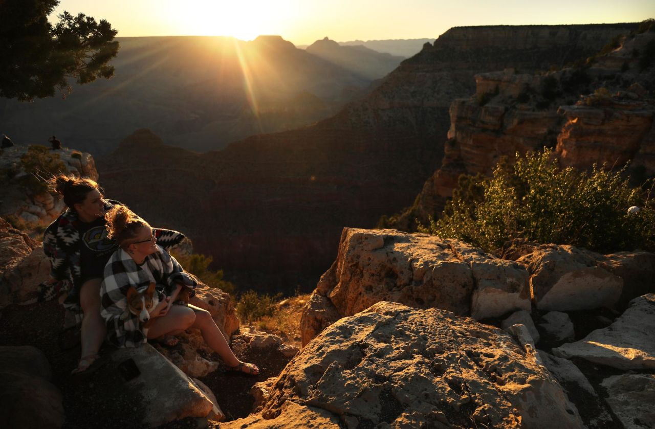 Park visitors watch the sunrise along the south rim of the Grand Canyon on Monday. Grand Canyon National Park has opened for limited hours and access.