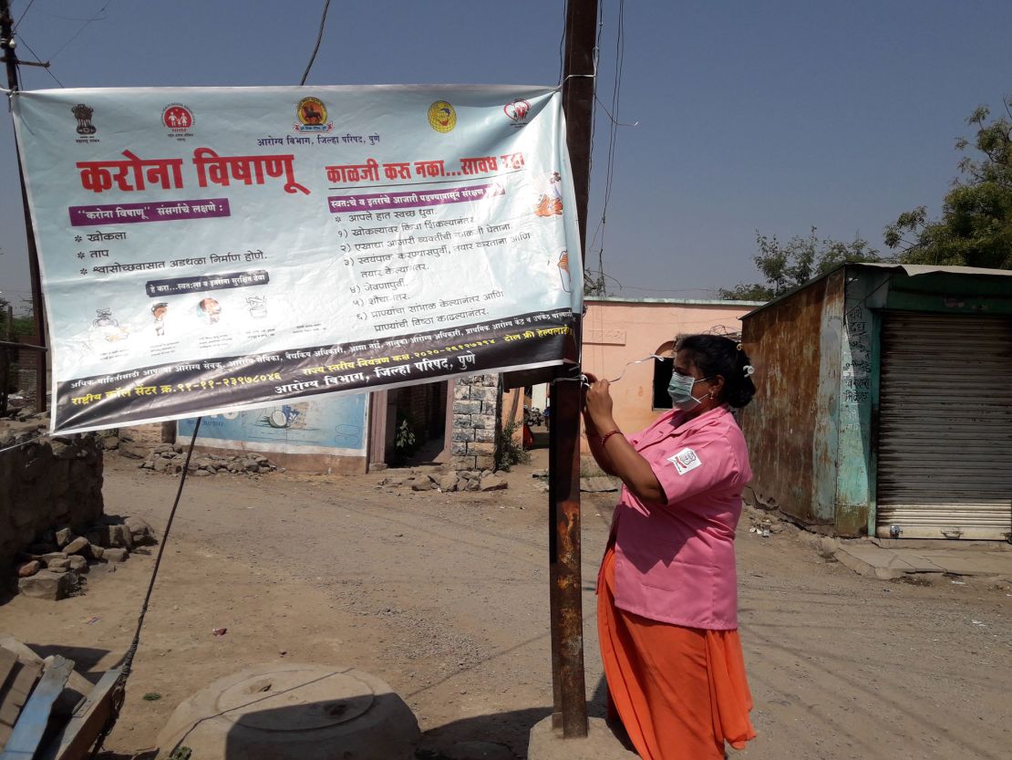 Rohini Pawar fixes a Covid-19 awareness banner in Walhe, a village in the Indian state of Maharashtra.