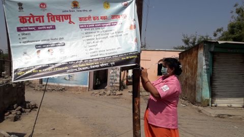Rohini Pawar fixes a  Covid-19 awareness banner in Walhe, a village in the Indian state of Maharashtra.