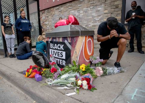 People gather and pray around a makeshift memorial in Minneapolis on May 26. It was near the site where Floyd was taken into police custody the previous day.