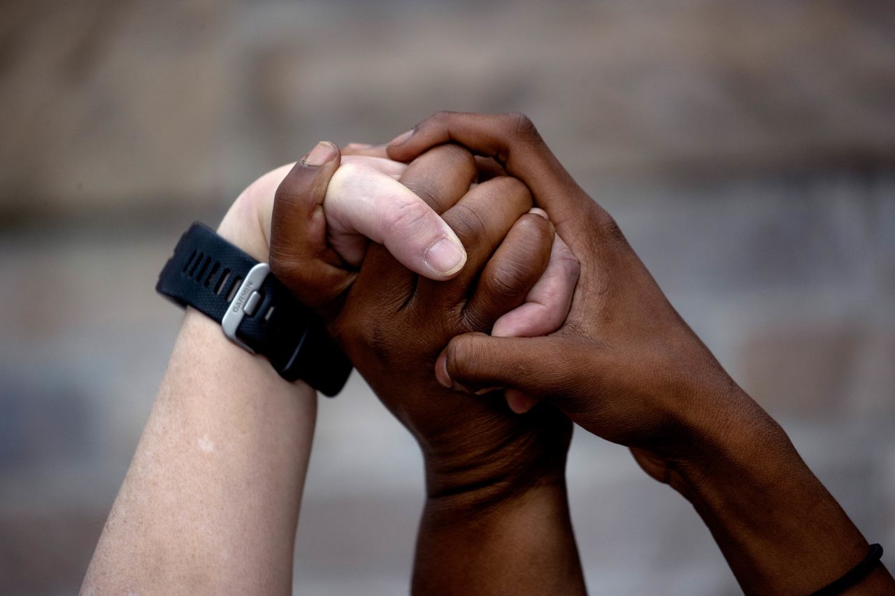 Three women join hands in Minneapolis as they pray around a makeshift memorial for Floyd on May 26.