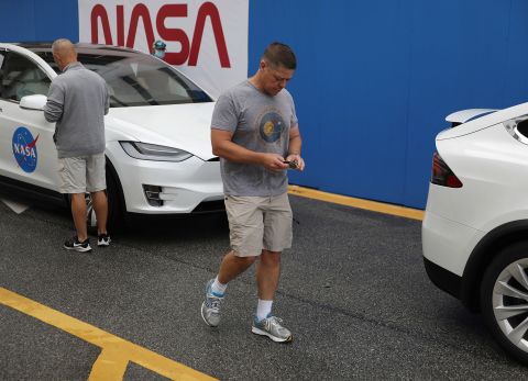 Hurley and Behnken prepare to place mission stickers on the windshields of their Tesla vehicles.