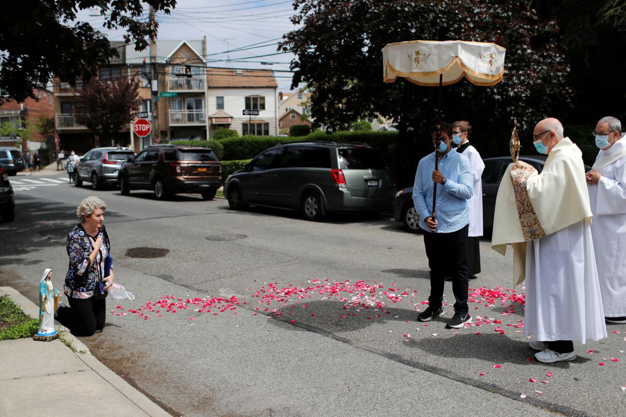 Krytyna Kopacki, left, prays with Deacon Robert Lavanco of Our Lady of Hope Catholic Church during a procession called the Blessed Sacrament on May 24. Lavanco has been visiting worshippers outside their homes while their church sanctuary is closed in New York.