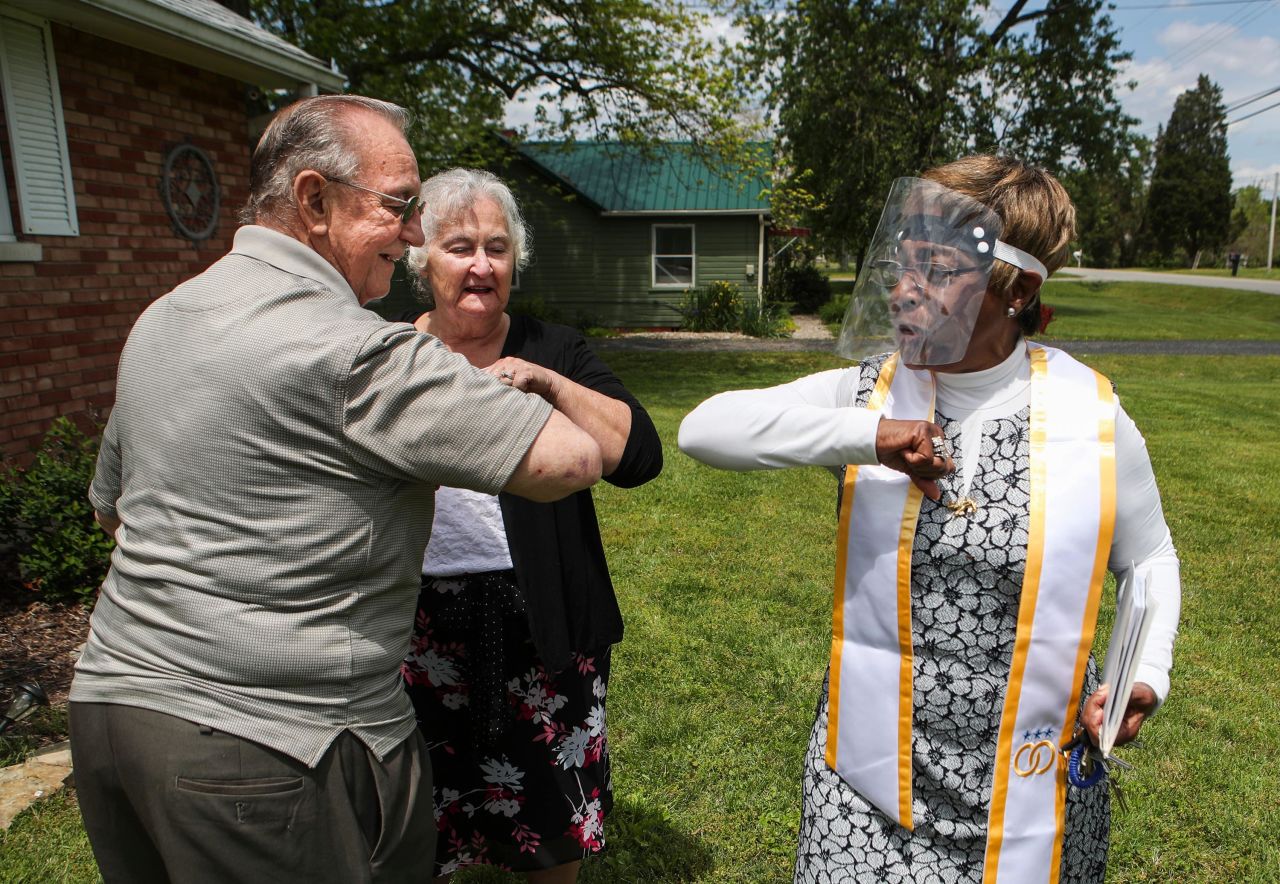 Karl Fretcher and JoAnn Payton get an elbow bump from minister Terri Foree after she married the couple in the front yard of Payton's home in Louisville, Kentucky, on May 12.