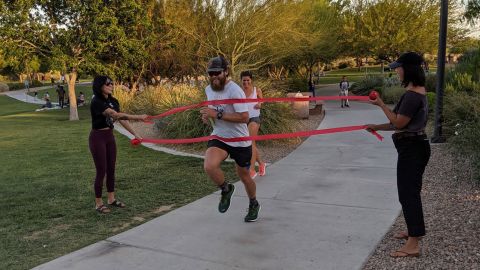 Makredes runs through red streamers to signify completed 50 miles.