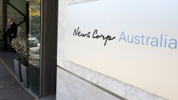 A security guard stands at the entrance to the News Corp. headquarters in Sydney, Thursday, May 28, 2020. Australia's largest newspaper publisher, News Corp., announced that most of its suburban and regional mastheads across the country will become digital-only next month due to the pandemic and digital platforms sharing their content. 