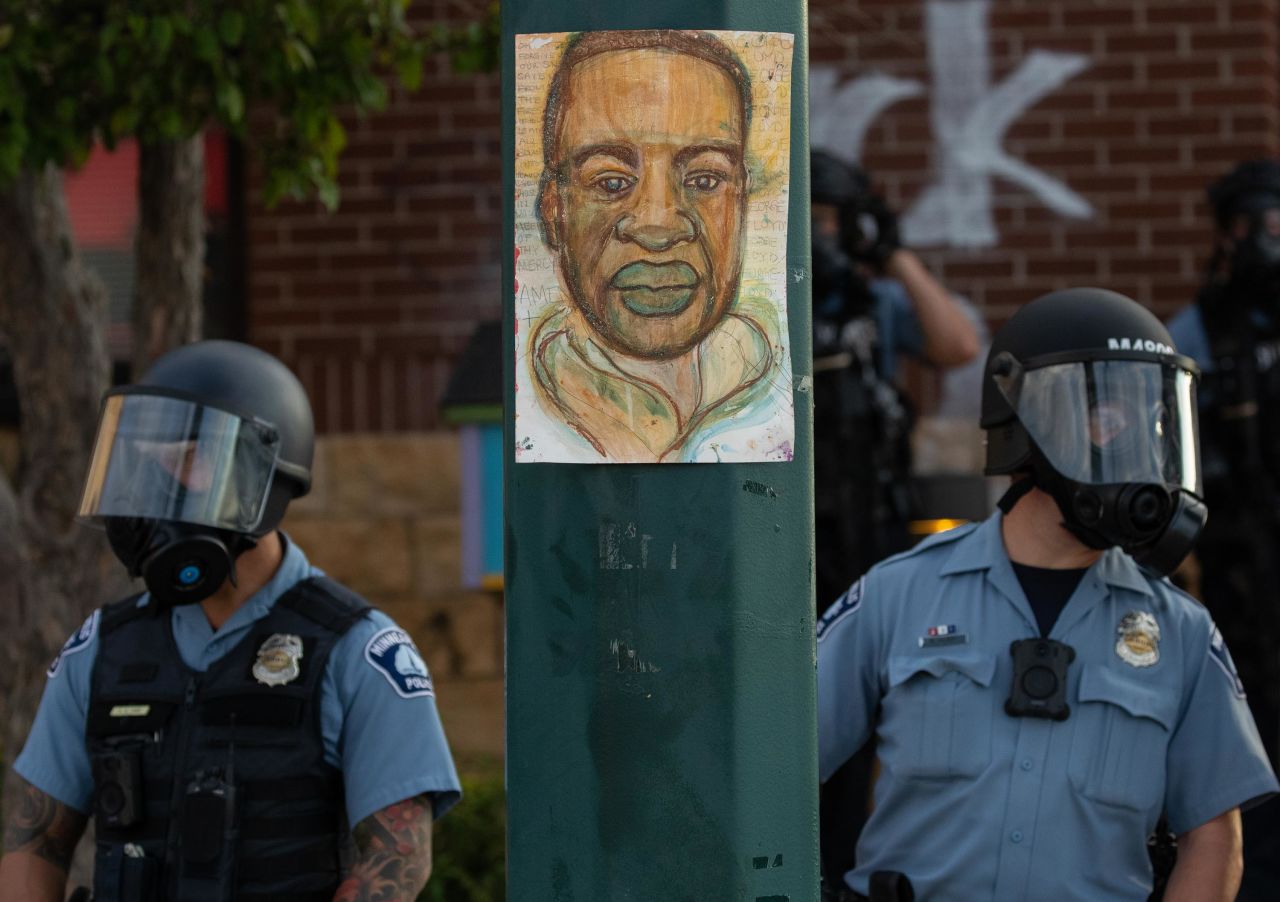 Minneapolis police stand by an illustration of Floyd as demonstrators rally on May 27.