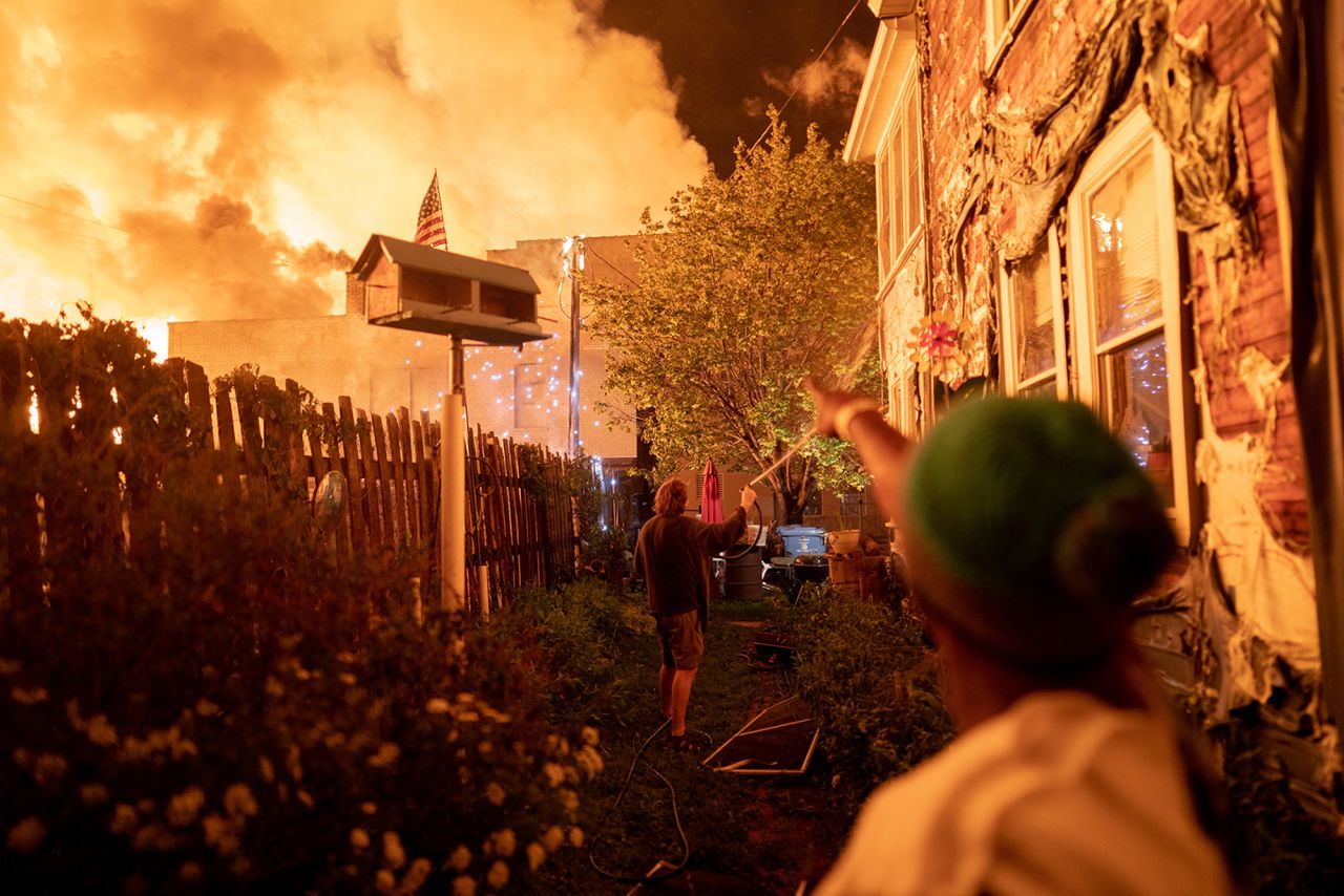 People use garden hoses and buckets to save homes in Minneapolis after rioters set fire to a housing complex under construction on May 27.