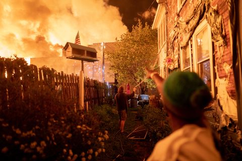 People use garden hoses and buckets to save homes in Minneapolis after rioters set fire to a housing complex under construction on May 27.