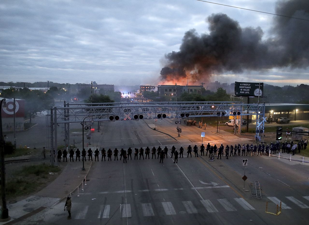 Police gather along Minneapolis' Lake Street early on May 29 as fires burned after a night of unrest.