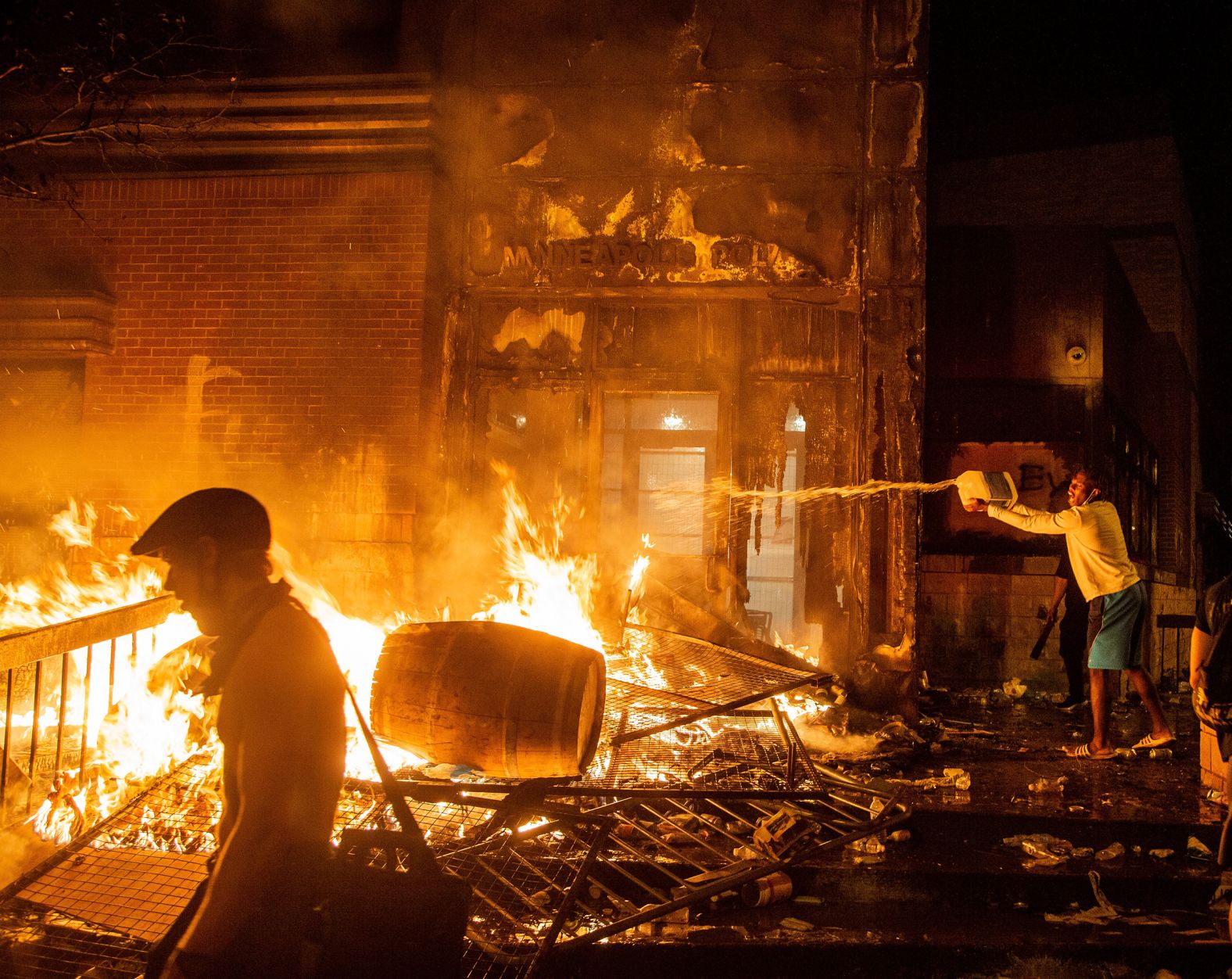 A protester dumps fuel on a fire at a Minneapolis police precinct on May 28.