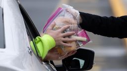 A cafeteria worker hands out free meals at Bensalem High School in Bensalem, Pennsylvania, Thursday, March 19, 2020.