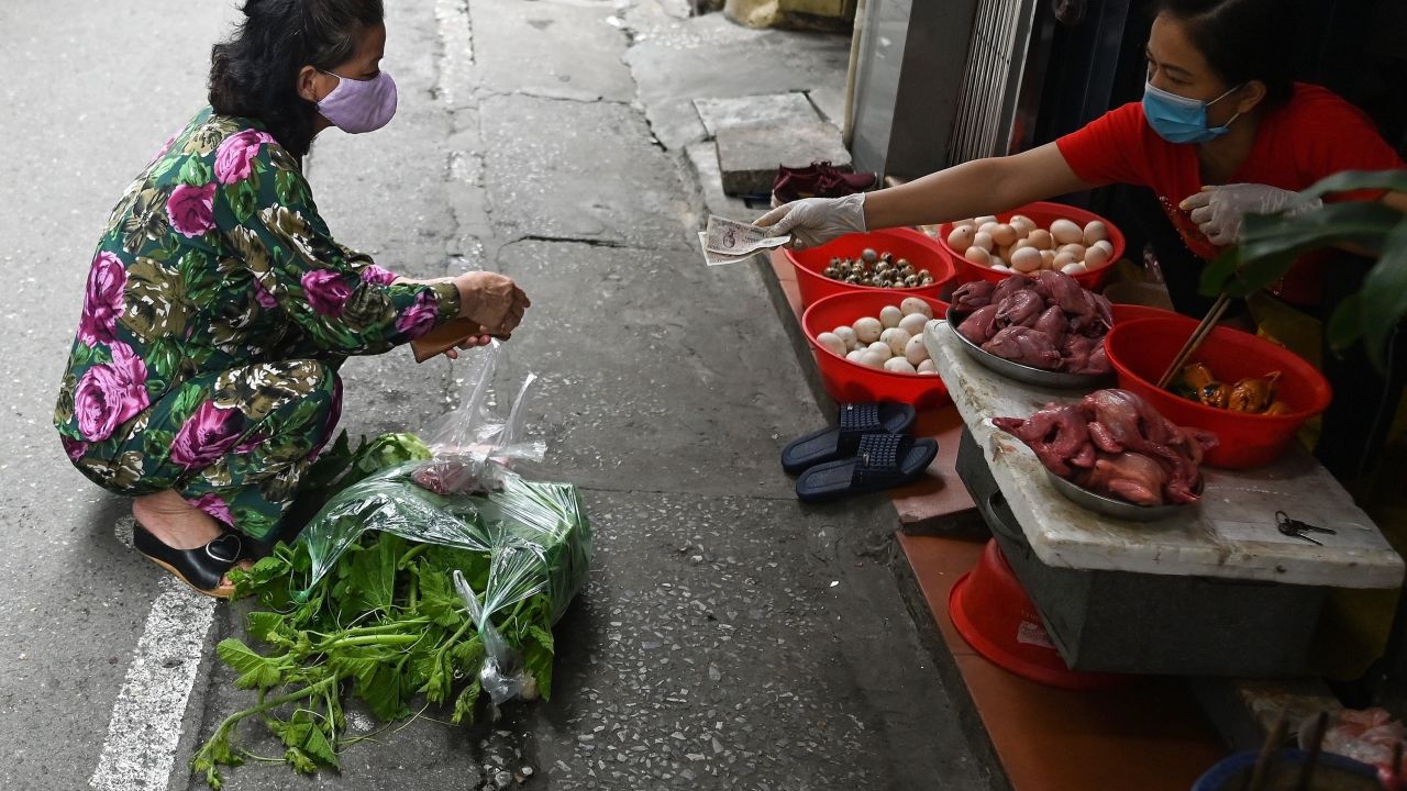 A woman practises social distancing while shopping for groceries from behind a line at a wet market in Hanoi.